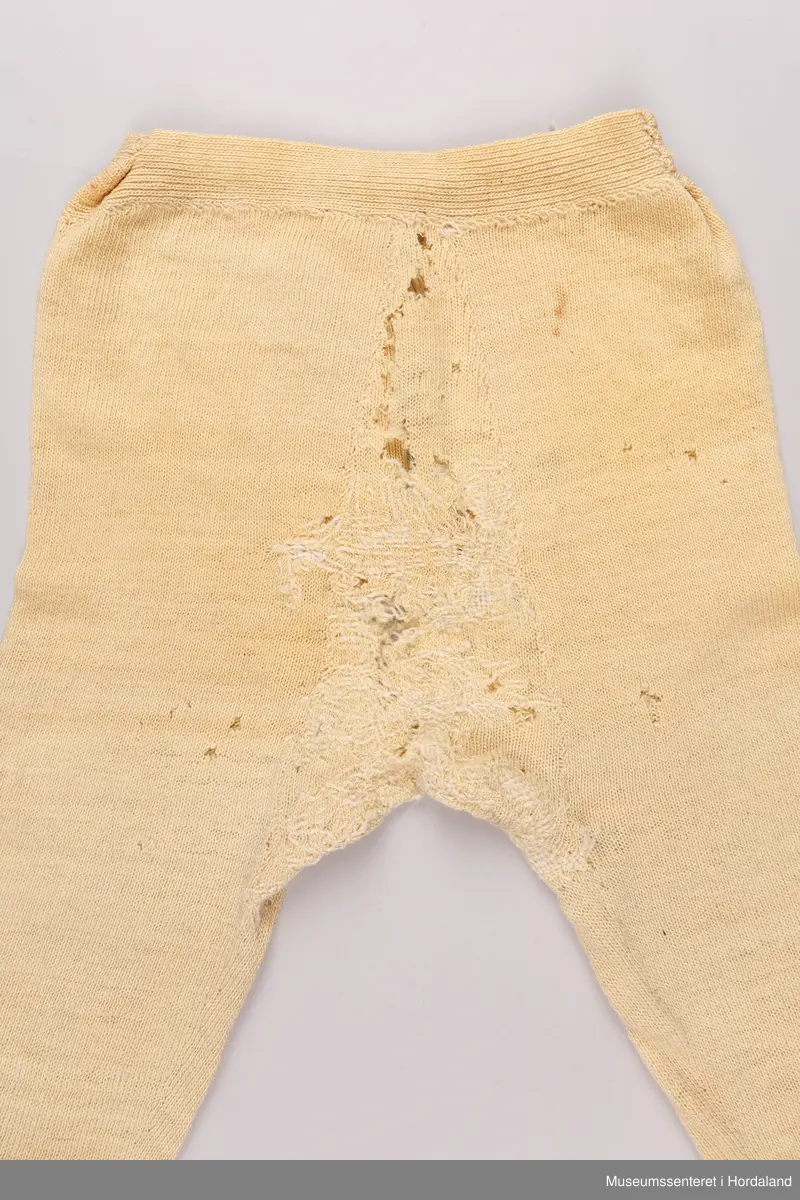 Strikka underbukse med bråt på bein og i livet, strikk og hemper i livet, og knappegylf. Buksa har mange hol, og er stoppa mange gongar, spesielt i skrittet i fronten av buksa.