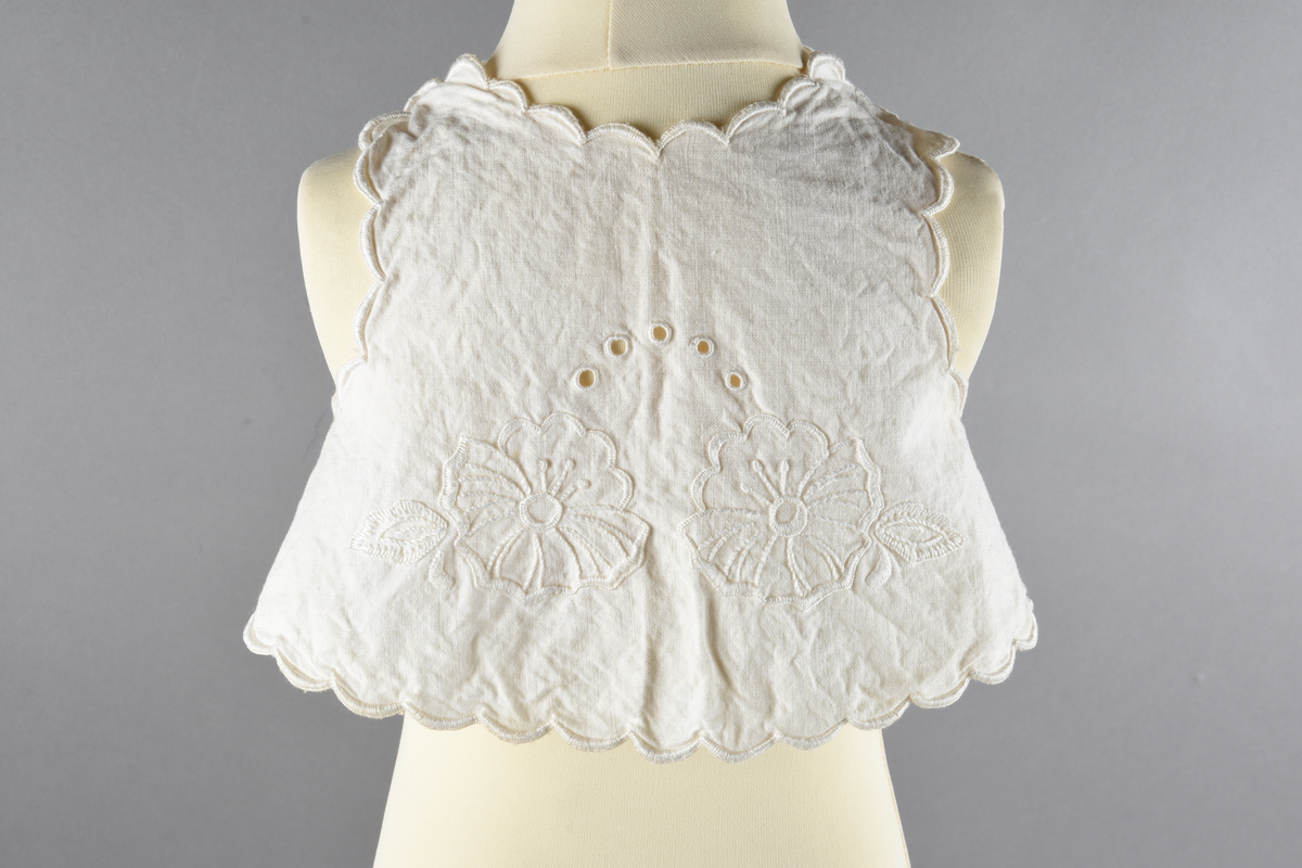 Vest til spedbarn. Bomull. Et stykke som har blitt sydd sammen for å lage ermehullene. Dekorert med broderier. Motiv av blomster.