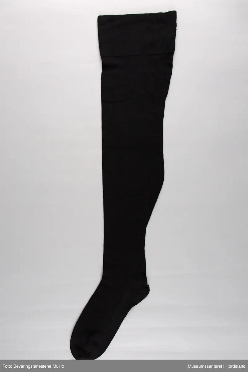 Svart Safa knestrømpe i ull/nylon, str. 9 1/2. Pakka i plastemballasje med blomsterdekor og blå og lilla fargefelt.
