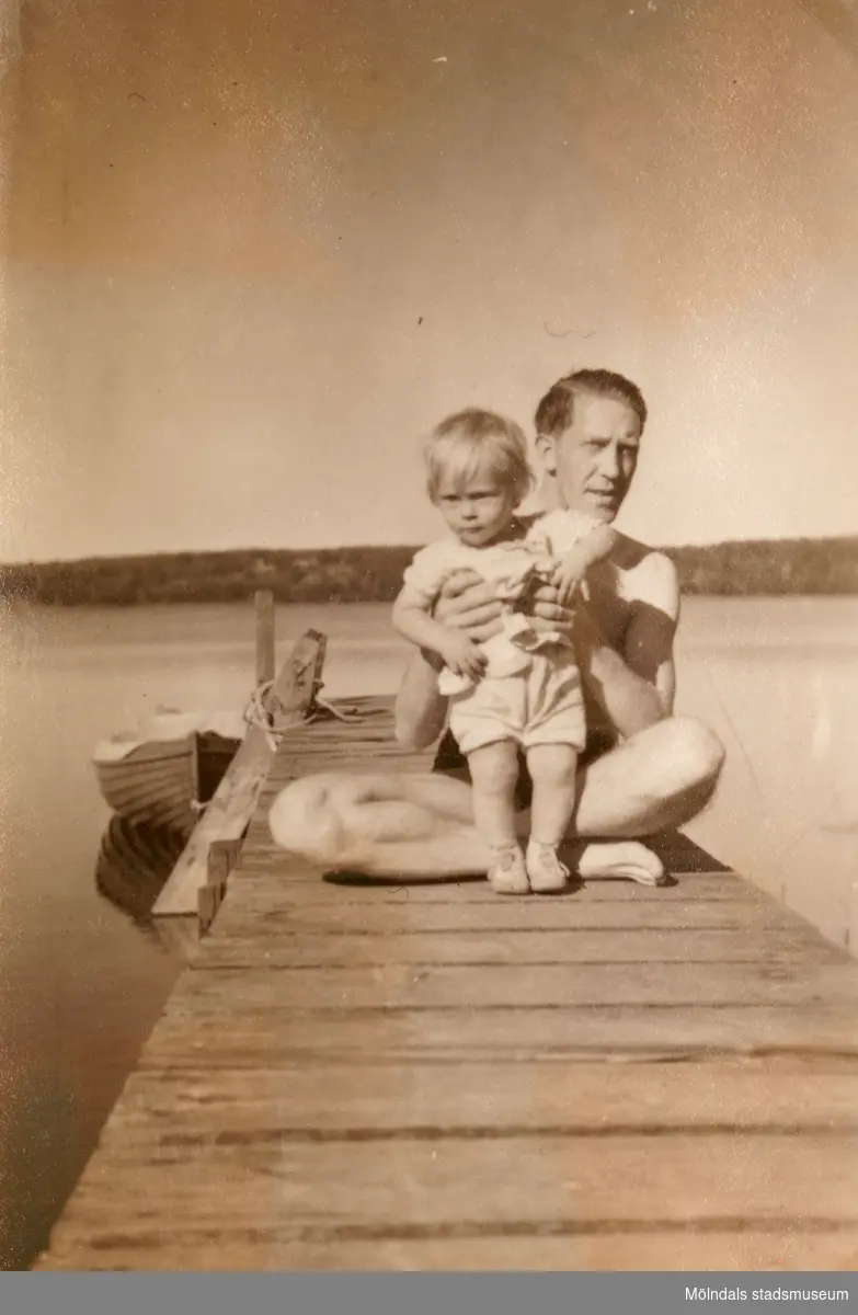 Bror "Petter" Pettersson (1913 - 1984) och dottern Eva (född 1944, gift Kempe) befinner sig på en brygga vid Tulebosjön år 1945. Till vänster, utmed bryggan, ligger en fastsurrad eka.