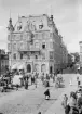 Jonn O Nilsons hus i Linköping 1898. Byggnaden uppfördes 1892-94 efter ritningar av arkitektfirman Fritz Ulrich & Eduard Hallquisth. Byggnadens markplan förbereddes för butiker. På bilden ses Herdina Lindbergs konditori och J C Krouthéns manufakturaffär. Andra våningen inreddes för kontor, bland andra för stadens Post och Telegrafstyrelse. I de övre våningarna skapades en ståndsmässig bostad åt byggherren. I bildens förgrund ses torghandel på Stora torget.