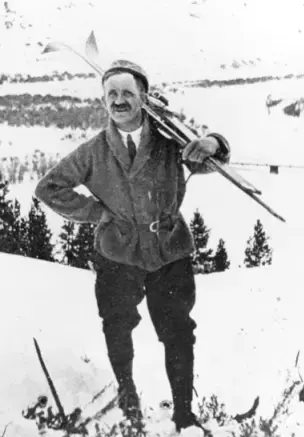 Svart hvitt foto, poserer i  vinterlandskap i vinterklær, med slips og ski over skuleren