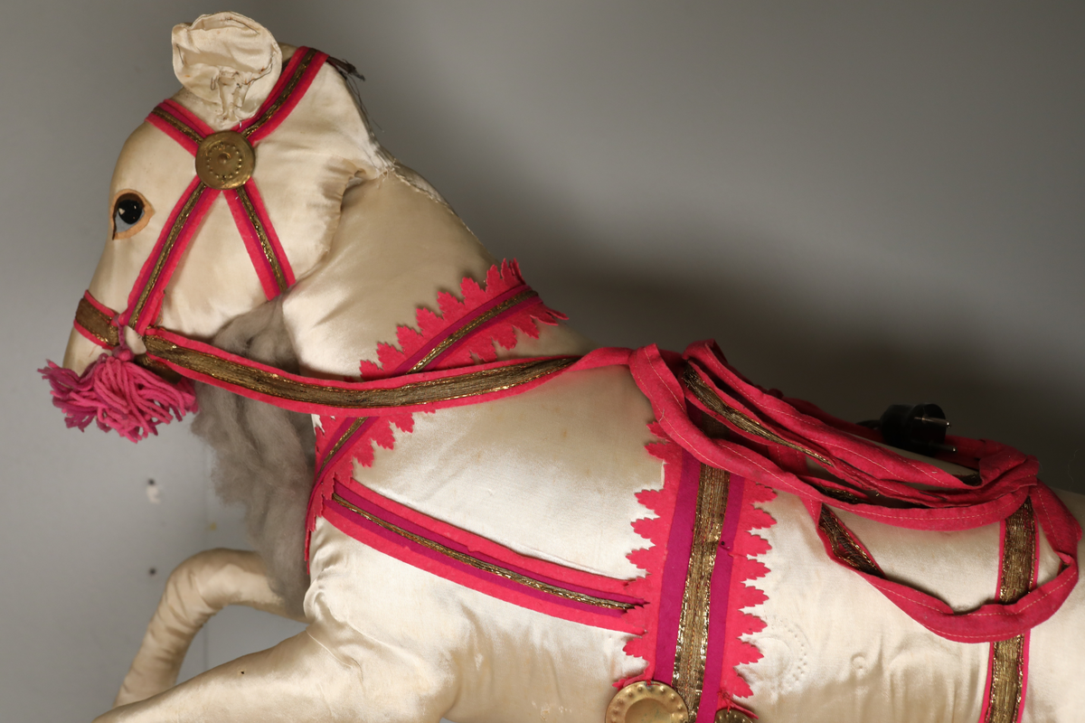 Utstillingsfigur montert på plate. Figuren er utformet som et reinsdyr i hvitt, silkeaktig stoff med brune klover og filtøyne. Geviret er surret inn med gullbånd og har sokler til lyspærer i taggene. Geviret er avtagbart. Reinsdyret har seletøy i rosa og lilla filt med gulltråd og runde metallplater. Juletrelysene til geviret er Philips 14v. Det stikker ender av ledninger ut av både kroppen og geviret. 

Reinsdyret består av flere deler:
a - kropp montert på plate med metallstøtte foran og bena skrudd fast bak. På et tidspunkt har noen stiftet fast papir over ytterkantene av det originalet stoffet.
b - gevir med plass til 8 lyspærer
c - gevir med plass til 7 lyspærer
d - løs pyntedusk
e - grå ledning
f til u - 16 lyspærer