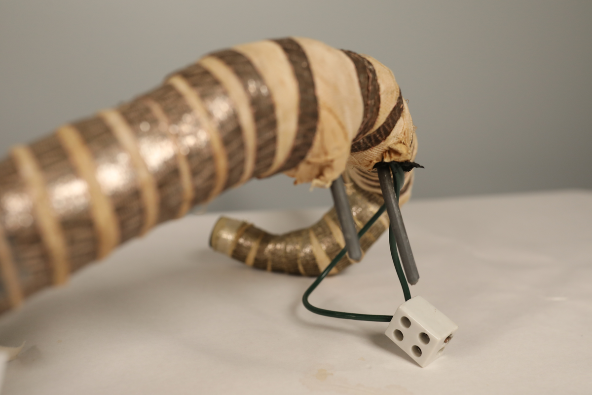 Utstillingsfigur montert på plate. Figuren er utformet som et reinsdyr i hvitt, silkeaktig stoff med brune klover og filtøyne. Geviret er surret inn med gullbånd og har sokler til lyspærer i taggene. Geviret er avtagbart. Reinsdyret har seletøy i rosa og lilla filt med gulltråd og runde metallplater. Juletrelysene til geviret er Philips 14v. Det stikker ender av ledninger ut av både kroppen og geviret. 

Reinsdyret består av flere deler:
a - kropp montert på plate med metallstøtte foran og bena skrudd fast bak. På et tidspunkt har noen stiftet fast papir over ytterkantene av det originalet stoffet.
b - gevir med plass til 8 lyspærer
c - gevir med plass til 7 lyspærer
d - løs pyntedusk
e - grå ledning
f til u - 16 lyspærer