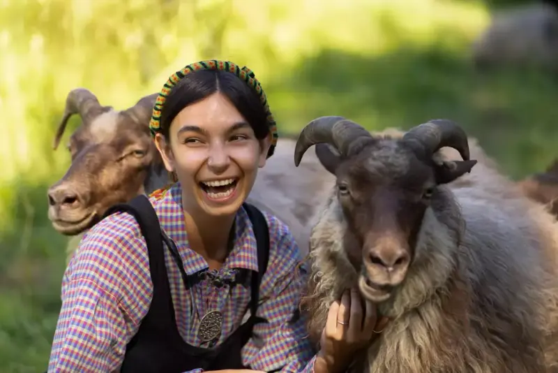 Smiling woman in traditional costume with sheep at the Open-Air Museum at Norsk Folkemuseum.