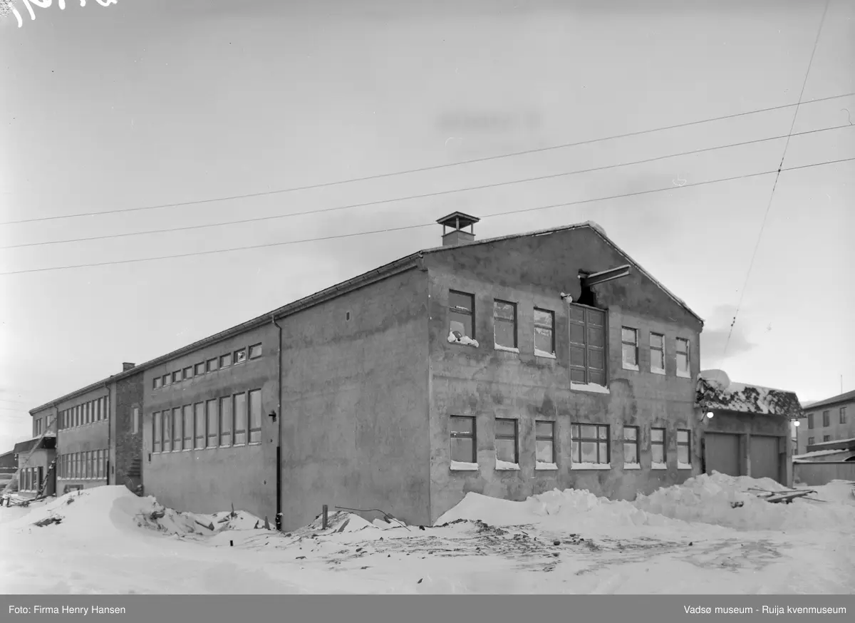 Nord-Norges Salgslag i Vadsø fotografert i januar 1957.  Bygningen ble oppført i 1956; arkitekt Kjell Magne Olsen og hovedentreprenør Rolf Bohinen.