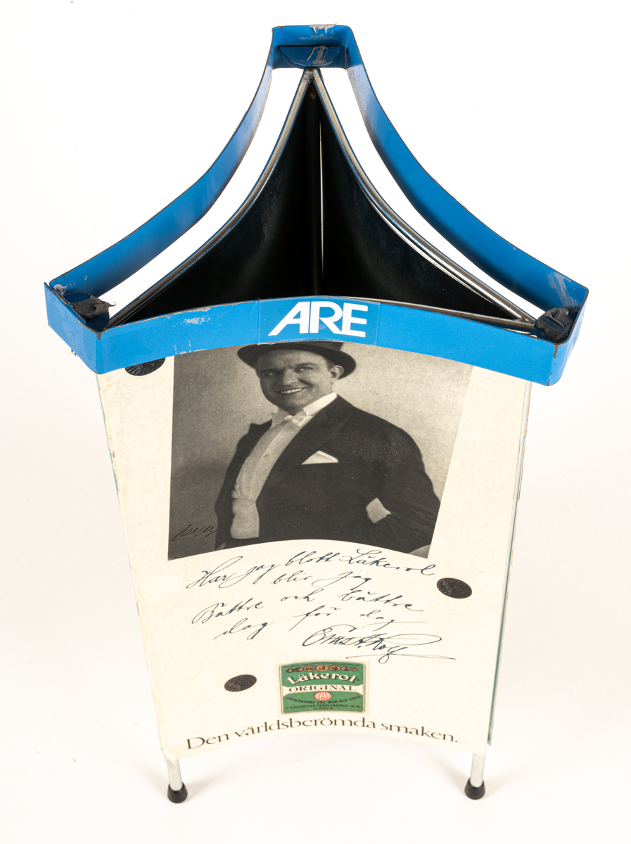 Reklamskylt, reklampelare på tre ben med plastfötter, i metall och papp, för Läkerol. Intygsreklam med citat från tre kändisar: Joséphine Baker, Ernst Rolf och Maurice Chevalier på de tre sidorna.