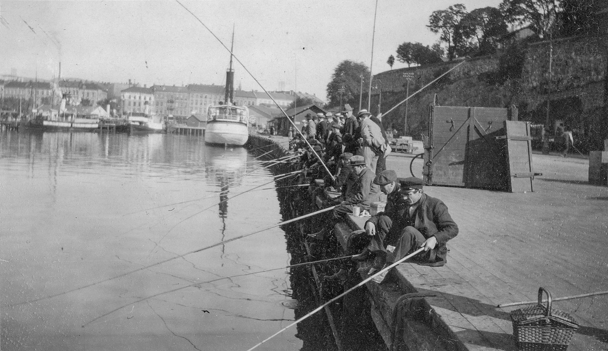 D/S Excellencen (Ex. Excellencen Toll, hjul-D/S Ystad)(b.1859, Motala Varf, Norrköping) liggende ved Festningsbryggen i Oslo havn. Fiskere med stenger sitter på kaien i forgrunnen.