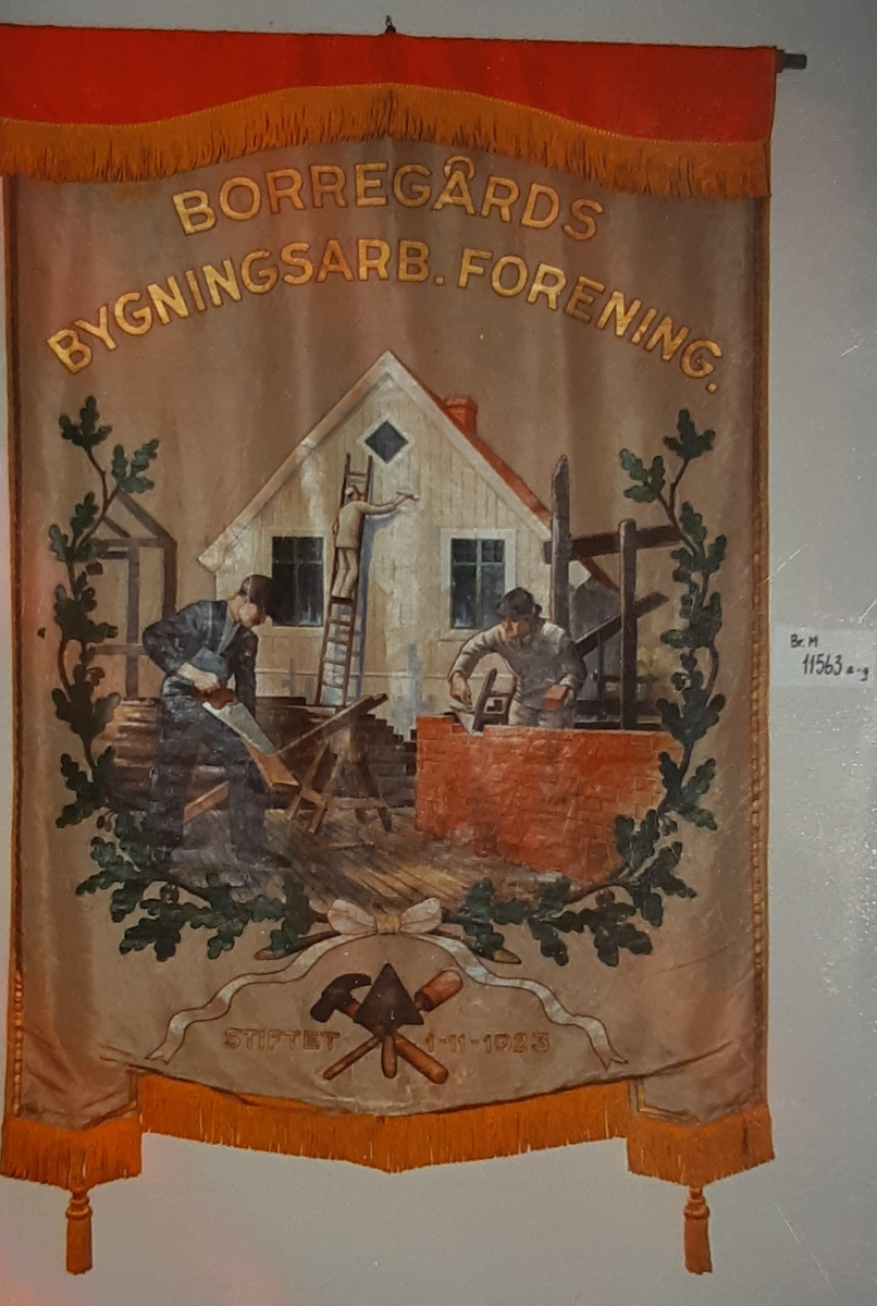 Forside: tre menn i arbeid på et hus, innrammet av ekeløvkrans, redskaper  (murerslev, hammer og pensel) nederst. Bakside: "Hus" m/stige, palett og redskaper. + tekst.
