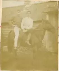 Motivet viser to unge menn på hesteryggen til en av Rostinfa