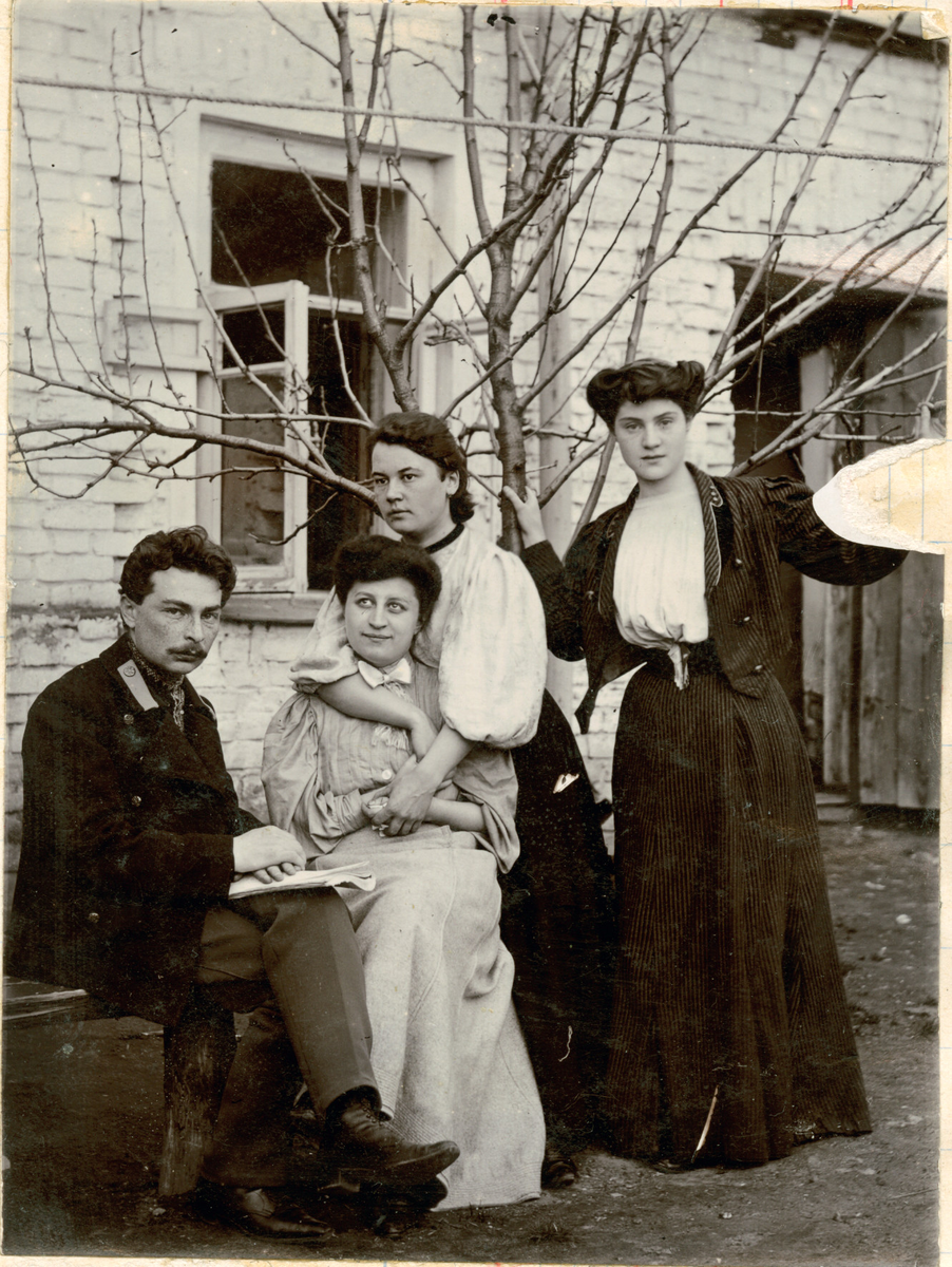 Motivet viser tre kvinner og en mann fotografert foran et tre. Julia Rostin ytterst til høyre. Mannen sitter med bena i kryss og hviler en skrivebok i fanget. En av kvinnene omfavner den andre kvinnen, mens den tredje lener seg til treet. I huset bak dem står vinduet og døren vidåpen.