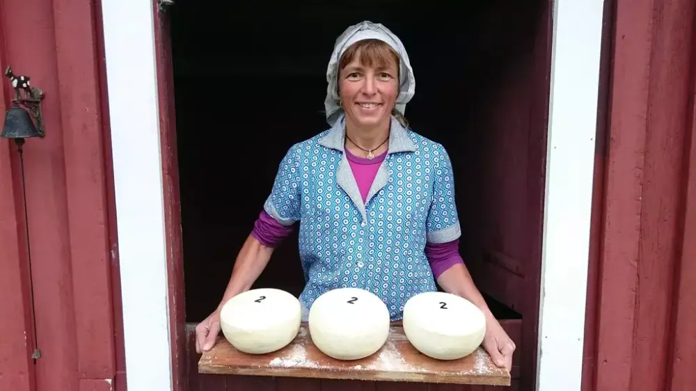 Budeie som viser frem tre hjemmelagde oster på et brett