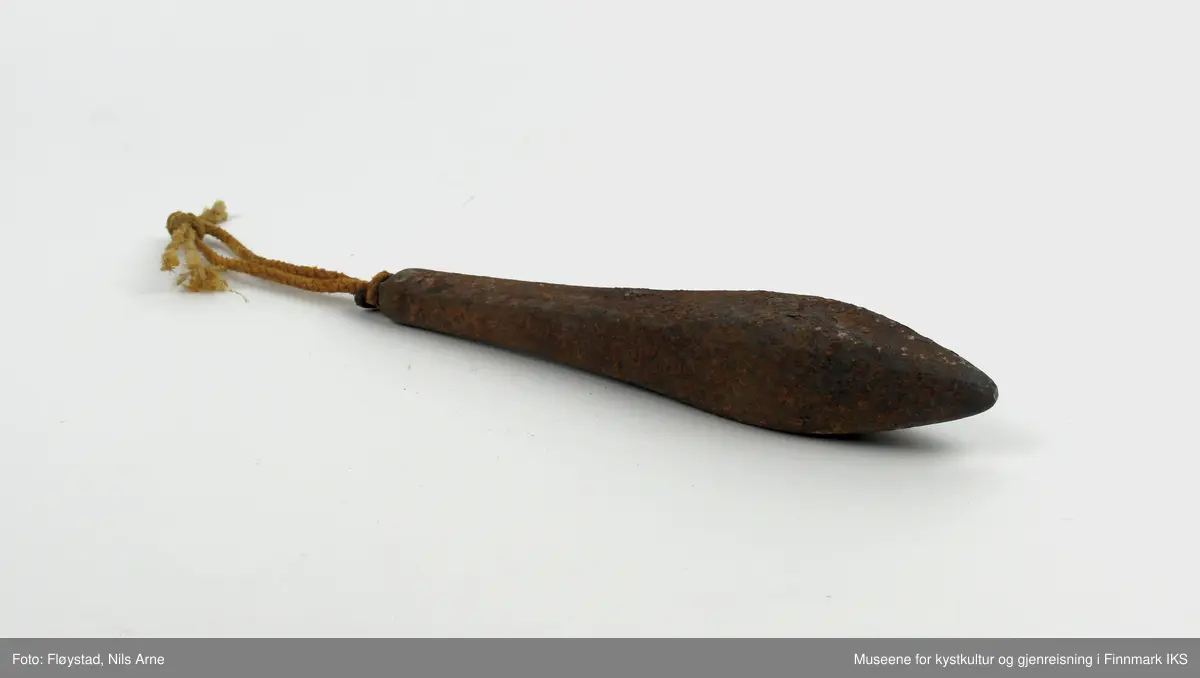 En avlang og dråpeformet jarstein med hempe, og i hempen er det festet et tau. På den ene siden av jarsteinen er tallet "6" gravert, som angir vekten på steinen (600 gram).