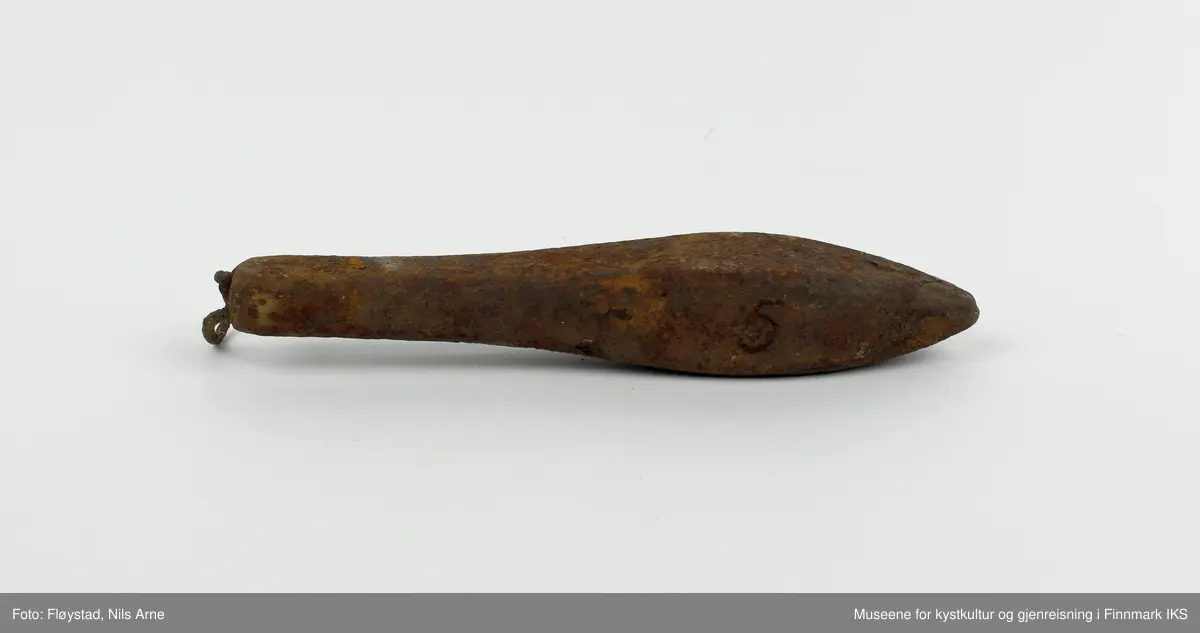 En avlang og dråpeformet jarstein med hempe. På den ene siden av jarsteinen er tallet "5" gravert, som angir vekten på steinen (500 gram).