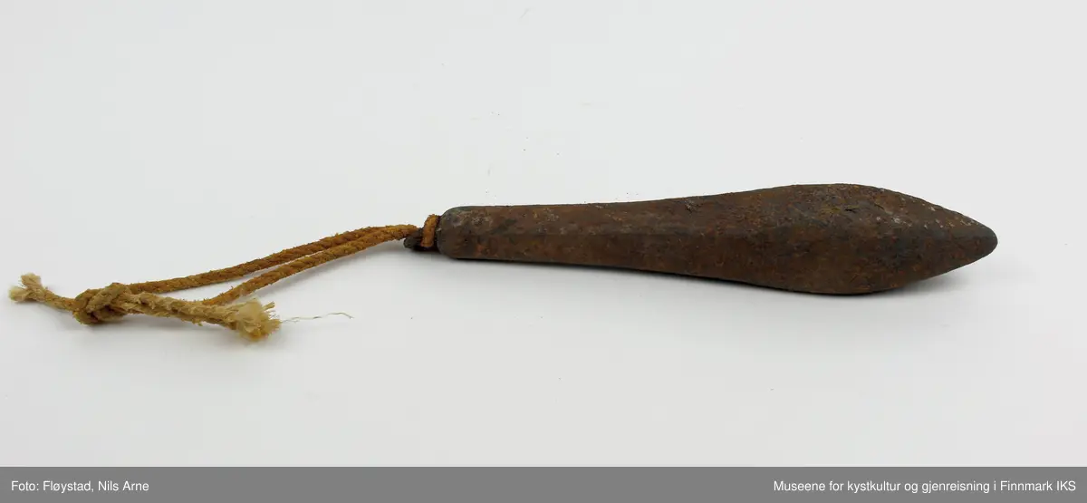 En avlang og dråpeformet jarstein med hempe, og i hempen er det festet et tau. På den ene siden av jarsteinen er tallet "6" gravert, som angir vekten på steinen (600 gram).