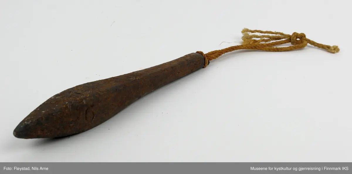 En avlang og dråpeformet jarstein med hempe, og i hempen er det festet et tau. På den ene siden av jarsteinen er tallet "6" gravert, som angir vekten på steinen (600 gram).
