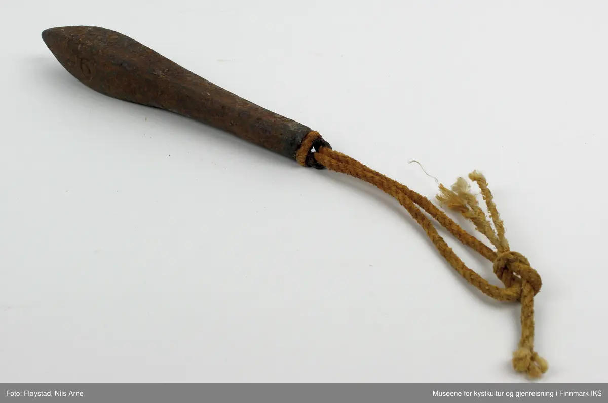 En avlang og dråpeformet jarstein med hempe, og i hempen er det festet et tau. På den ene siden av jarsteinen er tallet "6" gravert, som angir vekten på steinen (600 gram).