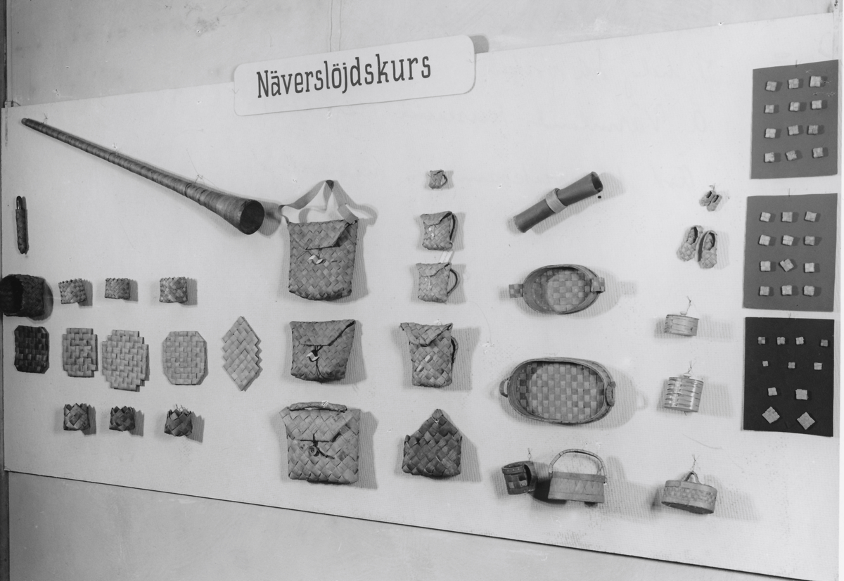 Väska med axelrem av snedflätad näver. Axelremmen består av näverremsor instuckna i ett virkat "galler" av svart bomullstråd. Lock med stängningsanordning.
