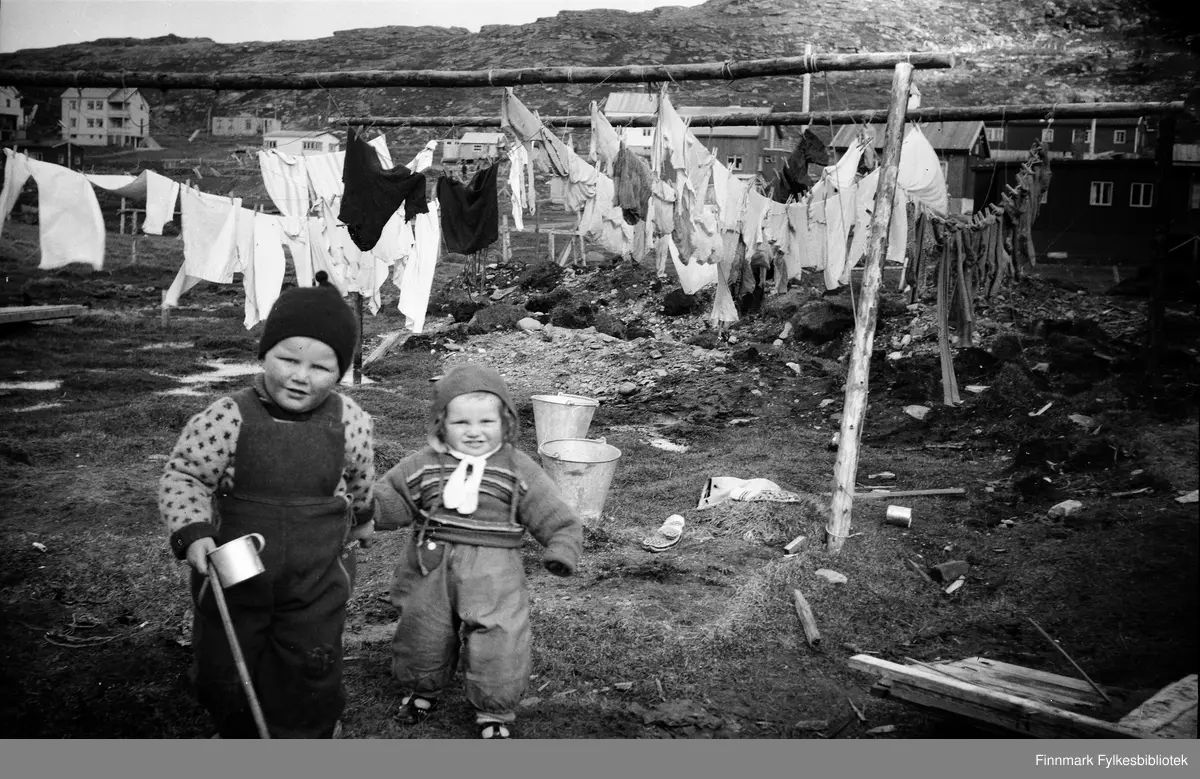 Havøysund ca. 1950. Odd og Randi Bjørnstad i forgrunn, i bakgrunn ser vi tørking av klær utendørs.