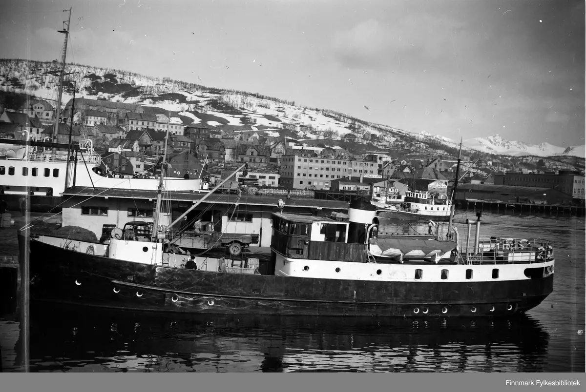 Fartøyet i forgrunnen er utvilsomt MS Salangen tilhørende TFDS. Bak sees også MS Grytøy tilhørende Grytøy Harstad Fergeselskap, men ble solgt til TFDS i 1974. "Grytøy" fremstår her i originalt utseende, som forteller at bildet er tatt før 1966, da hun fikk bygget om rorhuset. Stedet er Harstad. Vi ser bl.a. "Staal & Jern" forretningsbygget i bakgrunnen. 