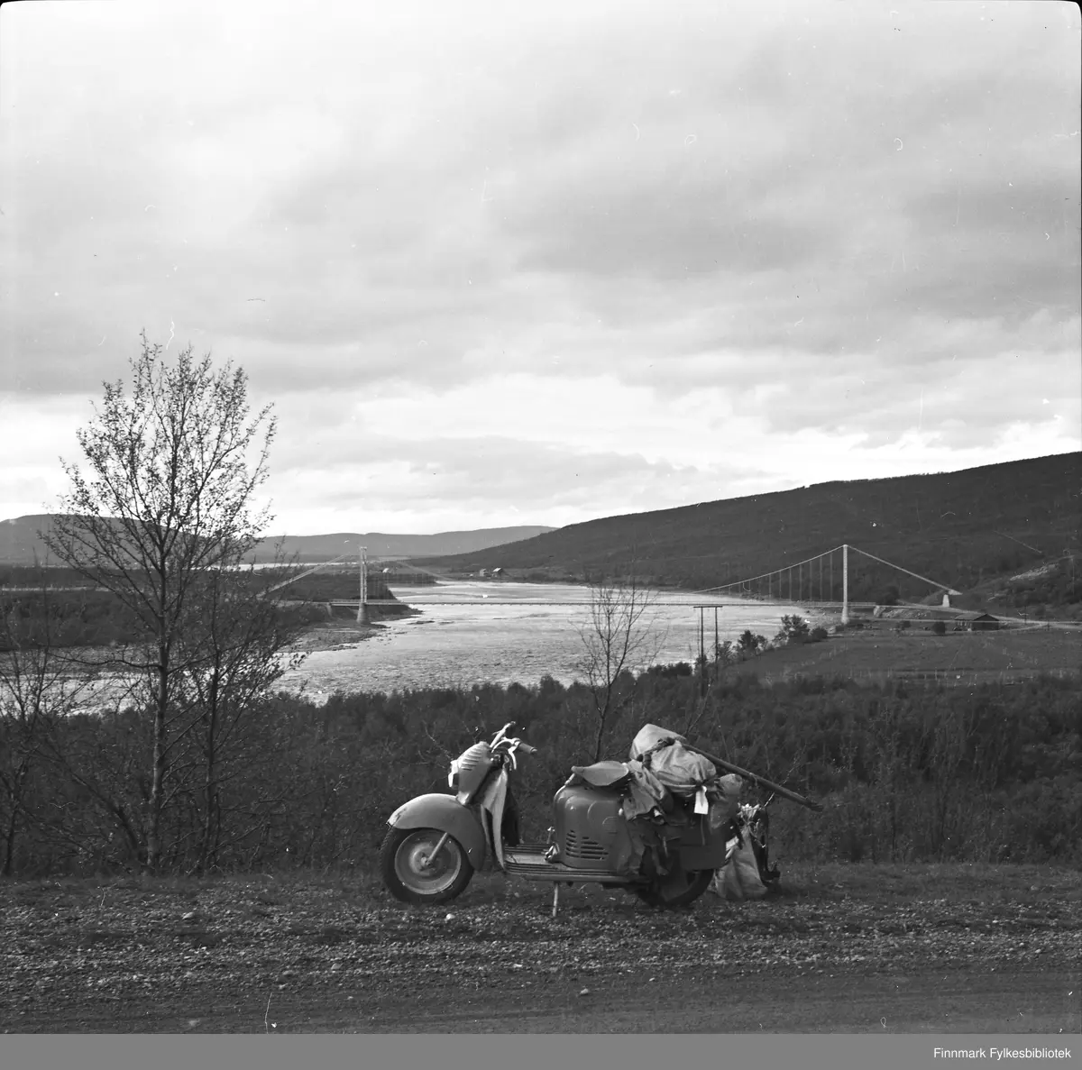 Scooterferie 1955. Scooteren er av det østerrikske merket Puch. Tana bru i bakgrunnen.