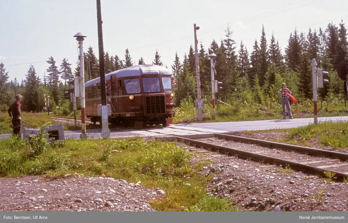 Dieselmotorvogn BM 87 02 på sidesporet Hauerseter-Gardermoen med utfluktstog for Norsk Jernbaneklubb - toget passerer planovergangen med E6