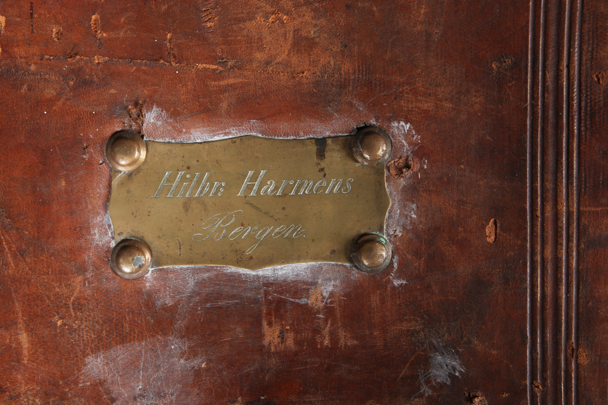 Rektangulær koffert med avrundede hjørner. To utvendige låser og to remmer med spenne. Fõret. Innvendig stor lomme i lokket.