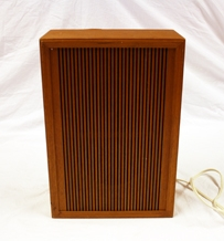 Høytaler. Rektangulær. Treverk. Teakfiner. Mangler bakside. Selve høytaleren festet på innersiden. Den er rektangulær med ovalformet forhøyning. Metall. Ledning festet til forhøyning. Forhøyningen har et åpent felt med tekstil. Fronten har langsgående riller.