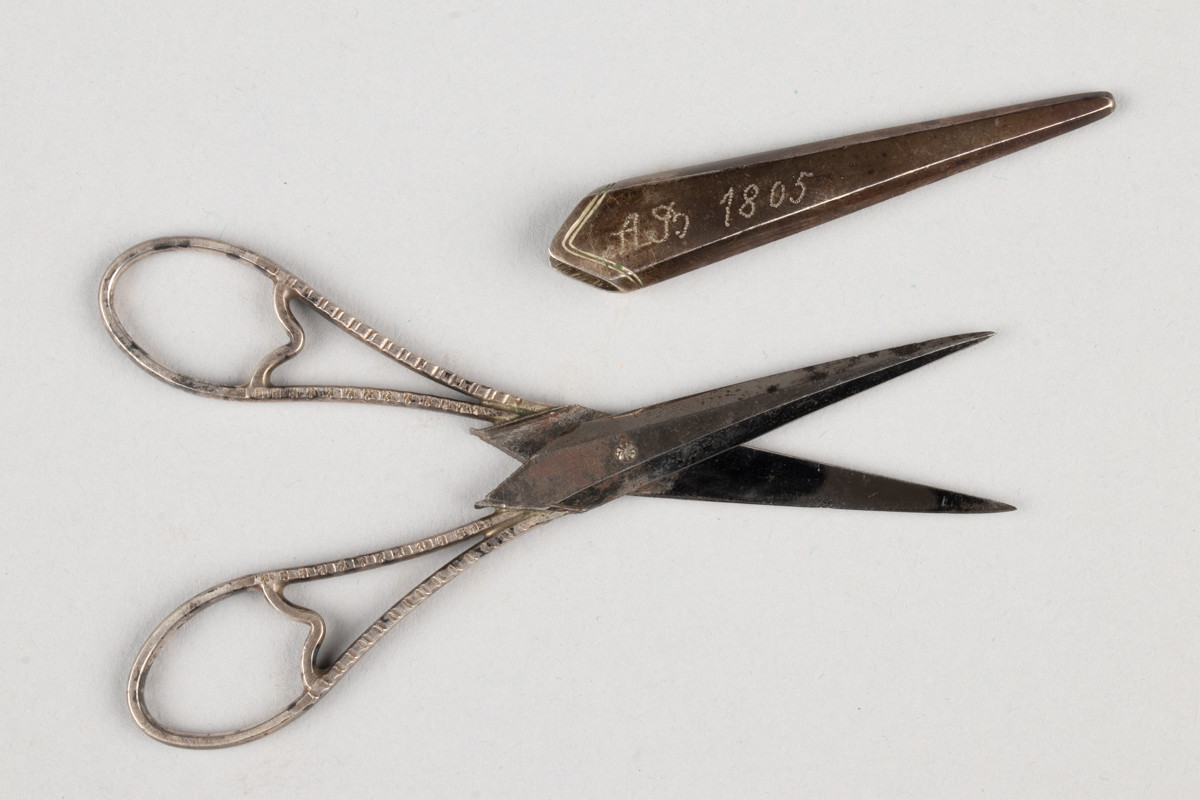 Liten saks for sying og brodering. Saksen har et etui med inngravert initialene til Anne Marlene Bruun og årstallet 1805