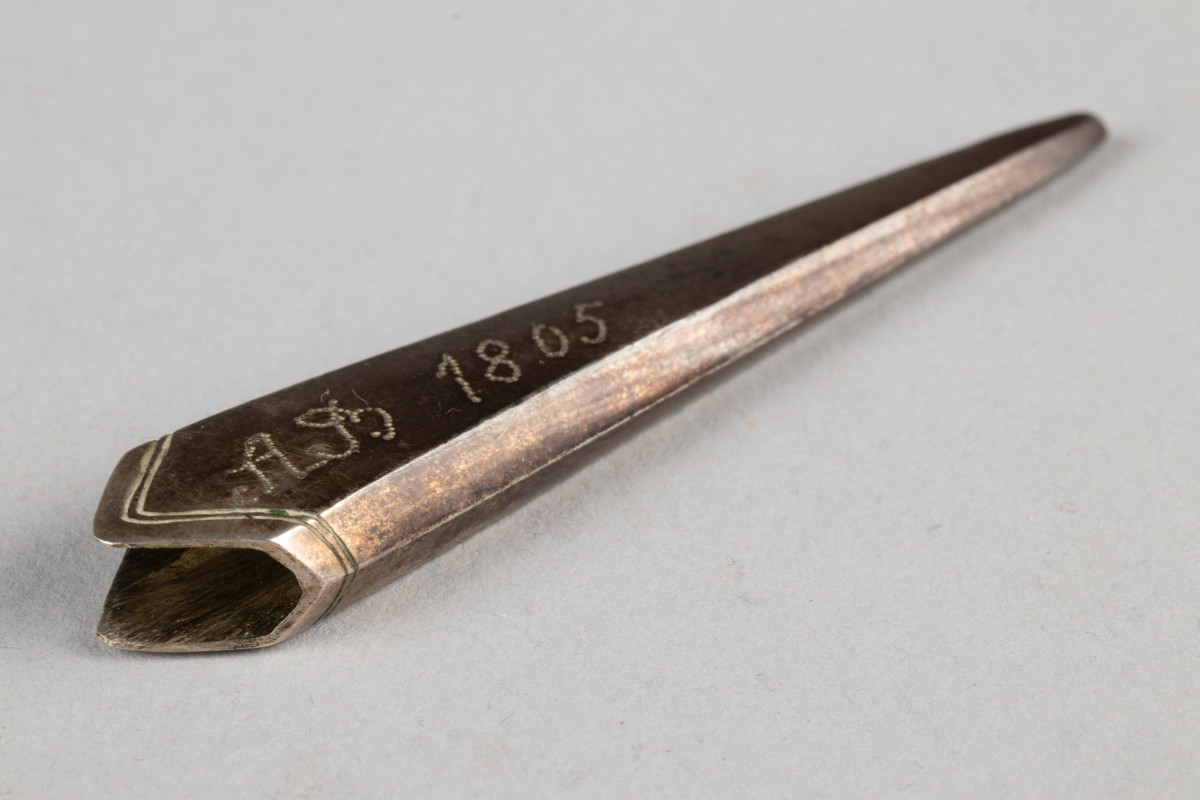 Lite etui til sysaks i metall. Initialene til Anne Marlene Rener Bruun og årstallet 1805 er inngravert