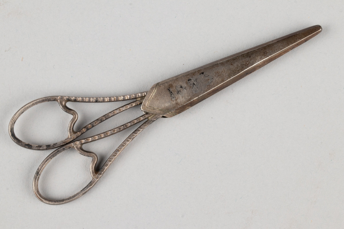 Liten saks for sying og brodering. Saksen har et etui med inngravert initialene til Anne Marlene Bruun og årstallet 1805