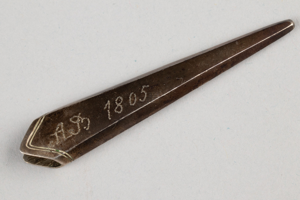 Lite etui til sysaks i metall. Initialene til Anne Marlene Rener Bruun og årstallet 1805 er inngravert