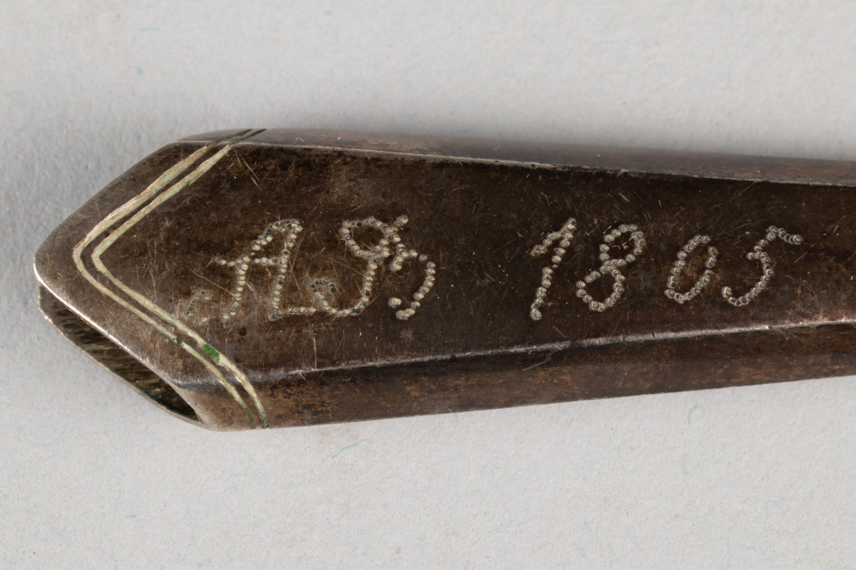 Lite etui til sysaks i metall. Initialene til Anne Marlene Rener Bruun og årstallet 1805 er inngravert