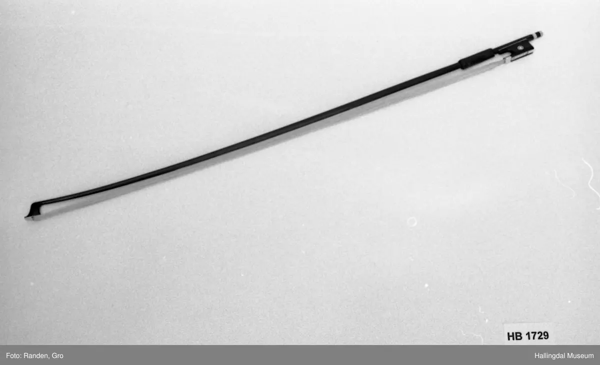 Tre, brunrød, lakkert. Hvite buehår. Sort håndtak. I treverket kan skimtes: LABER?TE