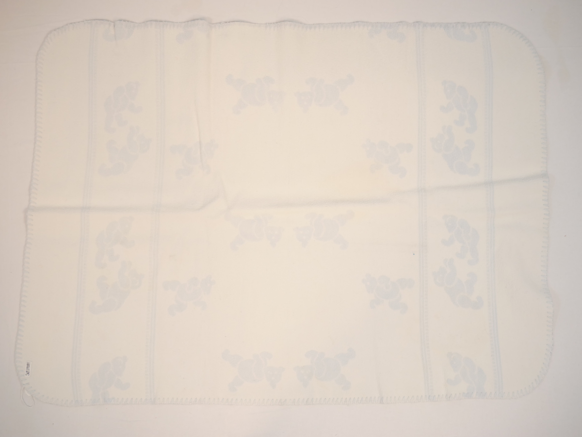 Teppet er kvitt på den eine og blått på den andre sida. På den blå sida er kvite bamsar, på den kvite sida er kvite bamsar.