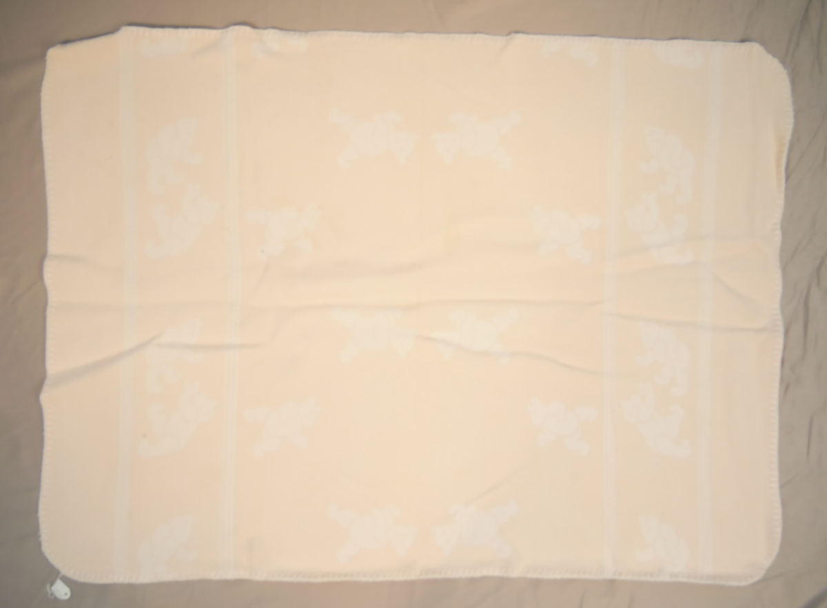 Teppet er kvitt på den eine og rosa på den andre sida. På den rosa sida er kvite bamsar, på den kvite sida er rosa bamsar.