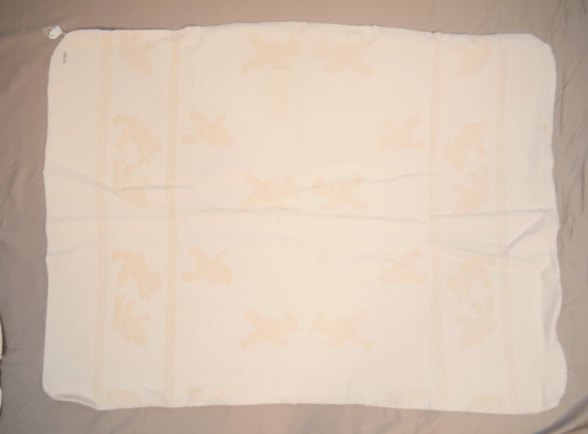 Teppet er kvitt på den eine og rosa på den andre sida. På den rosa sida er kvite bamsar, på den kvite sida er rosa bamsar.