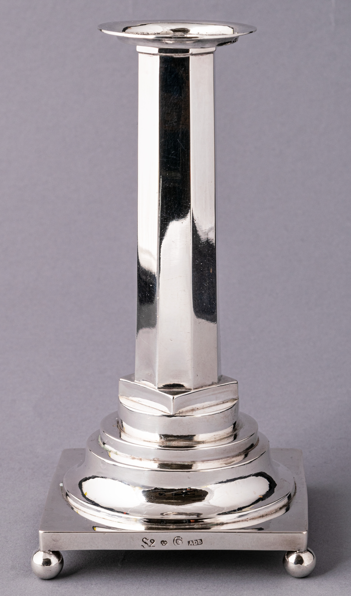 En av ett par gustavianska ljusstakar i silver stämplade Anders Dunderberg, Gävle 1800. Stram åttaformat ben med avtagbar manschett, rektangulär terrasserad fot med kulfötter. Mästarstämpel på fotens sida: S2 tre kronor G A.DB.