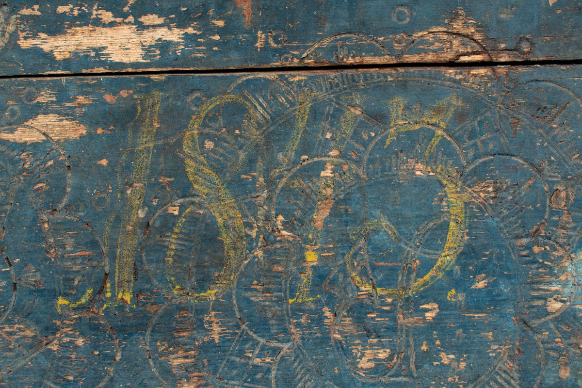 Håndhøvlet, malt og utskjært kiste i tre med jernbeslag og hektelås. Inne i kista er der tre rom, to store, og en liten skuff som har løsnet  på den ene siden.