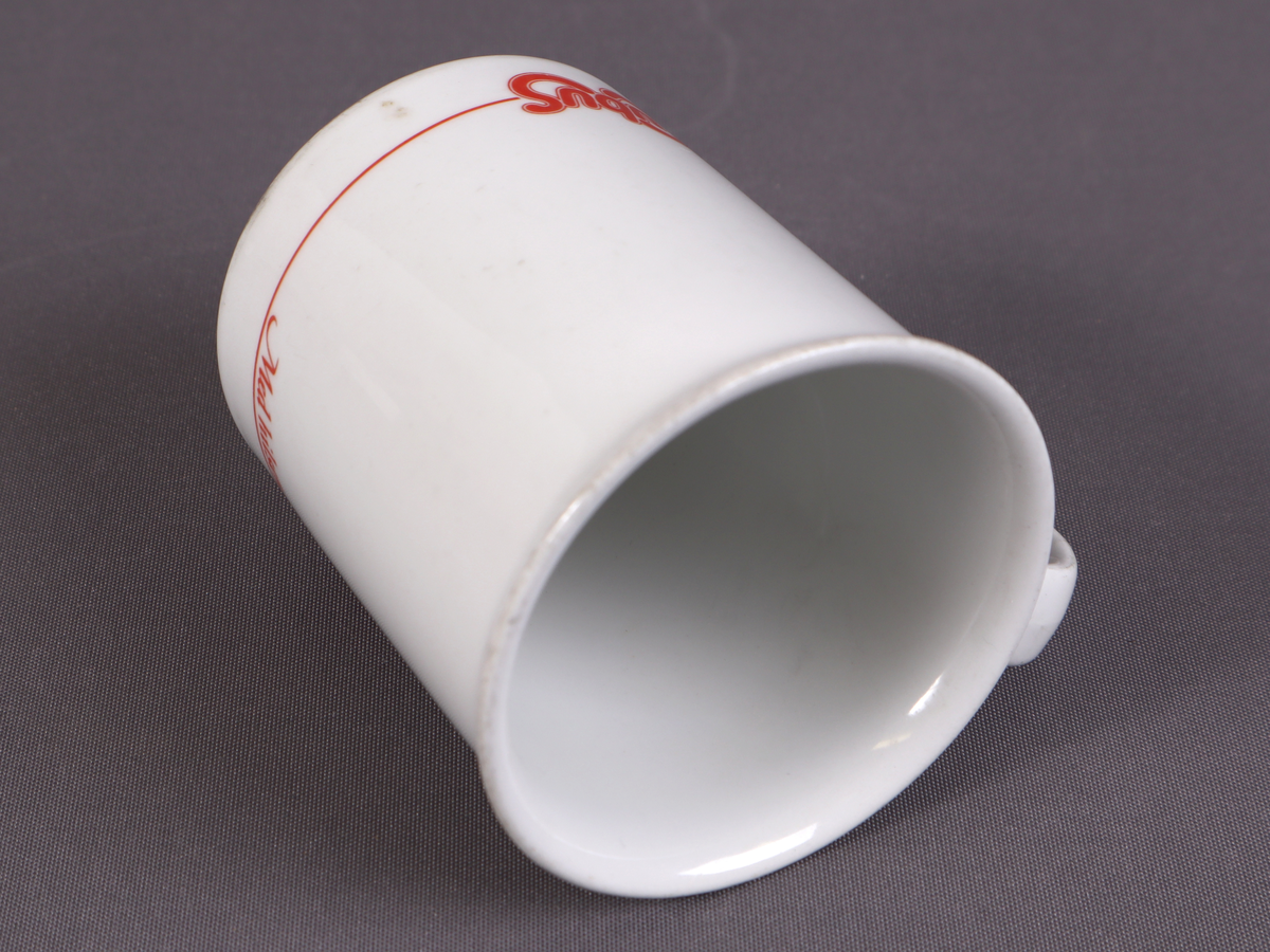 Kvitt krus med innskrifta "Med hilsen Cubus" i raud skrift.