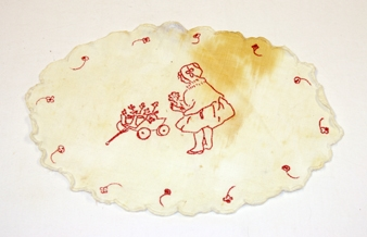 Brikke. Oval. Bomull. Tunger rundt kanten med tungebroderi. Blomster i stilkesting langs kanten. Illustrasjon av dame med trille med blomster. Stilkesting.  Brunlig flekk.