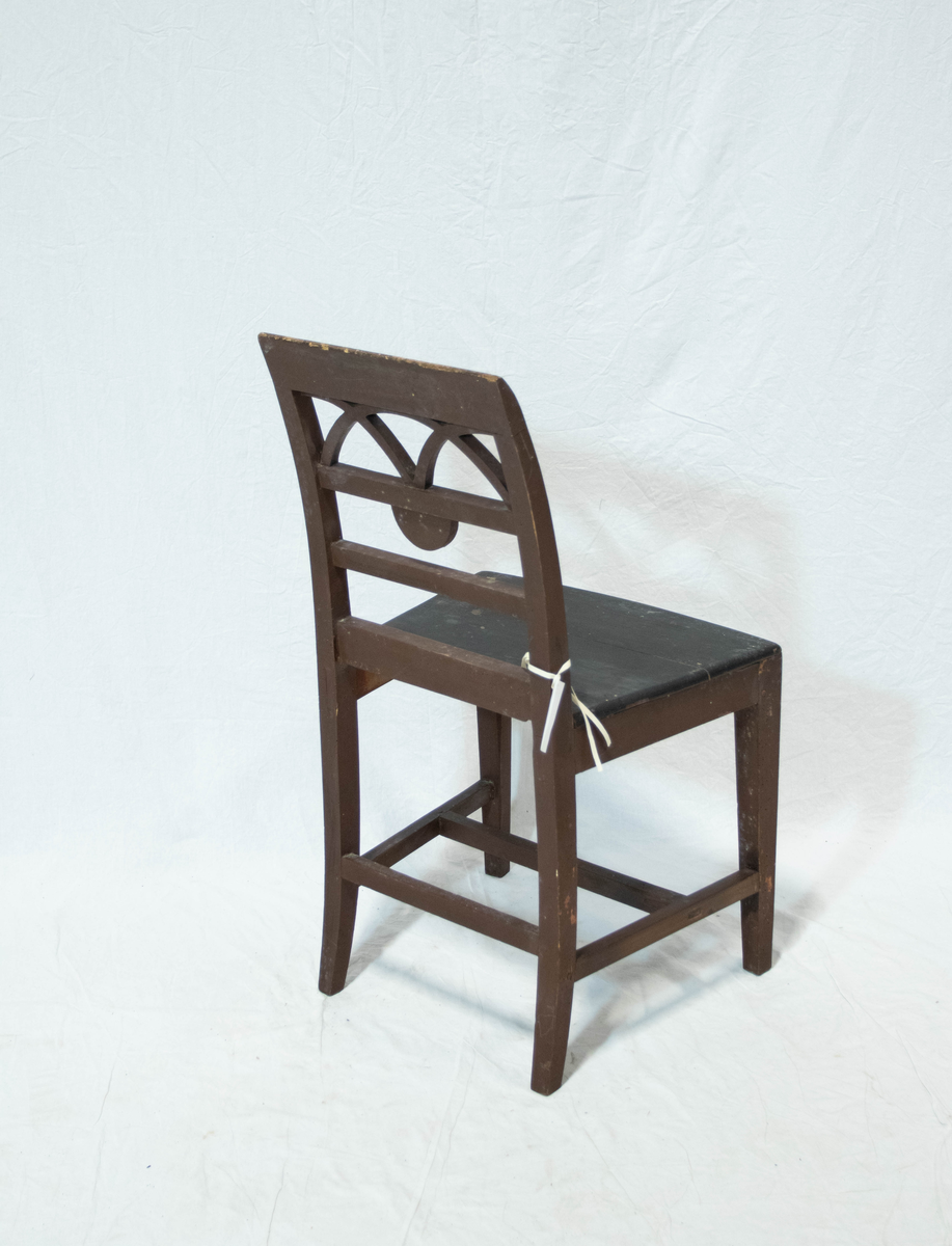 Trestol, hovedsaklig av bjørk men med sete av furu. Stolen har rester etter rødbrun maling. Stolen har rette forben og stramme C-formede akterstavene med firkantet tverrsnitt. Stolen har H-formet sprosse i tilegg til sprosse mellom bakbenene. Setet har buet front og ryggen har tre horisontale tversprosser sammen med et noe bredere skulderbrett. I øverste ryggfelt er det en halvsirkel som skjæres av to kvartsirkler. I midtre ryggfelt et det en halvsirkelformet vifte.