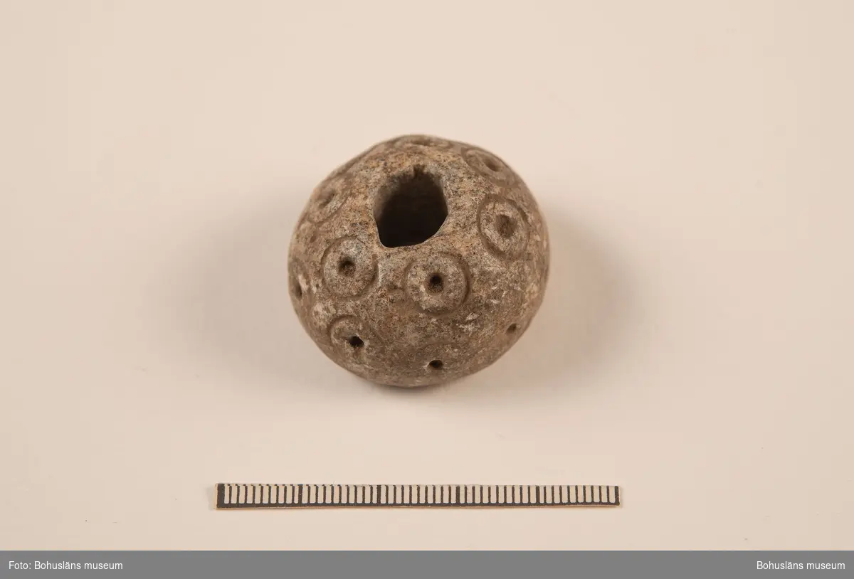 Sländtrissa, dekorerad med 18 st. små cirklar med mittpunkter.

Ur handskrivna katalogen 1957-1958: Sländtrissa. Diam. 3,5 cm. Ornerat med cirklar med mittpunkt. Halvklotformad. Föremålet helt. Myckleby. Orust

Landskap BOHUSLÄN

Lappkatalog: 1:27
