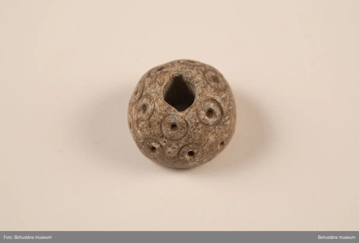 Sländtrissa, dekorerad med 18 st. små cirklar med mittpunkter.

Ur handskrivna katalogen 1957-1958: Sländtrissa. Diam. 3,5 cm. Ornerat med cirklar med mittpunkt. Halvklotformad. Föremålet helt. Myckleby. Orust

Landskap BOHUSLÄN

Lappkatalog: 1:27