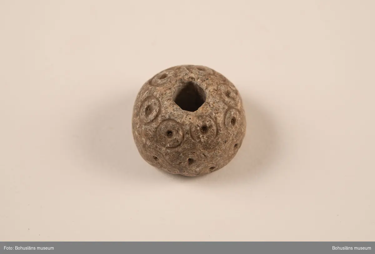 Sländtrissa, dekorerad med 18 st. små cirklar med mittpunkter.

Ur handskrivna katalogen 1957-1958: Sländtrissa. Diam. 3,5 cm. Ornerat med cirklar med mittpunkt. Halvklotformad. Föremålet helt. Myckleby. Orust

Landskap BOHUSLÄN

Lappkatalog: 1:27