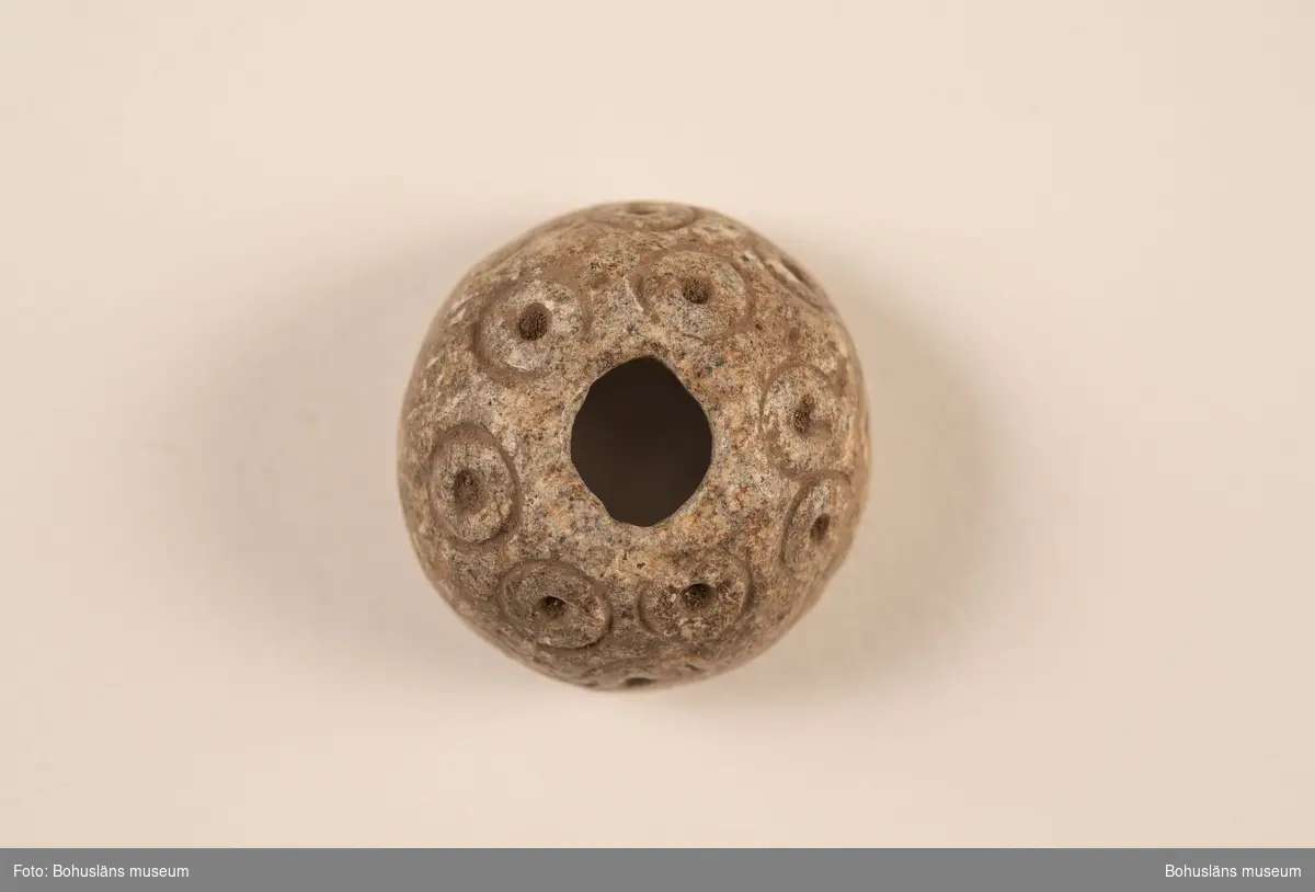 Sländtrissa, dekorerad med 18 st. små cirklar med mittpunkter.

Ur handskrivna katalogen 1957-1958: Sländtrissa. Diam. 3,5 cm. Ornerat med cirklar med mittpunkt. Halvklotformad. Föremålet helt. Myckleby. Orust

Landskap BOHUSLÄN

Lappkatalog: 1:27