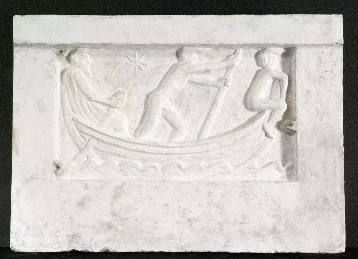 Skulptur, relief. Gips. Rektangulär form med sammanhängande bas och sidor samt utskjutande postament som tillsammans bildar ramverk till reliefscen i mitten: en båt vatten där en man ror, en gosse håller utkik och en gubbe styr. Bilden ska symbolisera "Livets båt". Förlaga till en av gavelrelieferna på "Rolfs spis". Baksida med upphängningsanordning i metalltråd. Tre sekundära spikar. Smutsig. "Rolfs spis" fullbordades 1913 av Ellen Roosval von Hallwyl som en gåva till sonen Rolf att placeras på egendomen Hildesborg utanför Landskrona. Spisen höggs i svensk blå marmor samt till relieferna vit cararramarmor. Vid Rolfs död 1964 kom spisen att placeras på Muramaris. Spisen behandlas i bland annat tidskrifterna Hvar 8 Dag samt Konst & Konstnärer 1913.
Nyreg 20130304 JE