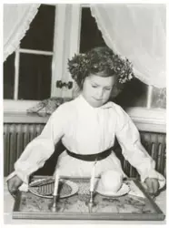 En flicka klädd i Luciaklänning, med en krans på huvudet, st