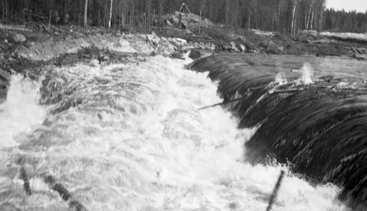 Tømmerfløting i elva Søndre Osa i Åmot kommune i Hedmark. Fotografiet er tatt våren 1936, ved den da nybygde kraftverksdammen ved Kvernfallet. I forgrunnen ser vi hvordan vannet og tømmerstokkene fløt over den avrundete damkrona. Den underliggende konstruksjonen, som vi ikke ser på dette bildet, var utført i armert betong. I 1936 var det innmeldt 383 088 tømmerstokker til fløting fra Osensjøen og tilflytende vassdrag. 28 prosent av stokkene ble levert ved Slemma, 10 prosent ved Nordre Osa, 7 prosent ved Brøa, 13 prosent ved Ena med Ulvsjøvassdraget, 7 prosent ved Tverrena og resten, 35 prosent, ble levert ved Osensjøens strender. Alt dette tømmeret. pluss noe av et kvantum på 72 506 stokker som var levert ved Søndre Osa, skulle passere den nye kraftverksdammen ved Kvernfallet. Aktørene i fløtinga var naturlig nok spente på om dammen kom til å bli et hinder der stokkene satte seg fast på eller like nedenfor dammen. Det skjedde ikke. Kvernfalldammen kom ikke til å skape nevneverdige problemer for tømmerfløtinga.