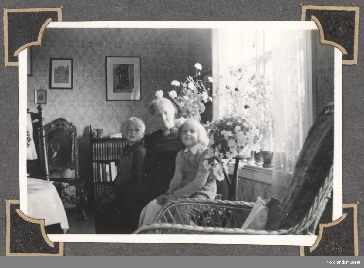 Bestemor sitter med to unger i stuen